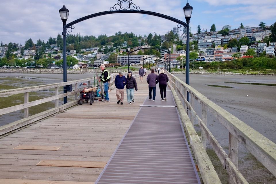 Visitors walk along the White Rock Pier where new accessibility priority signs will be installed following council approval.