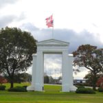 Peace Arch monument with Canadian and U.S. flags above, framed by trees at Peace Arch Park on the Canada–U.S. border.