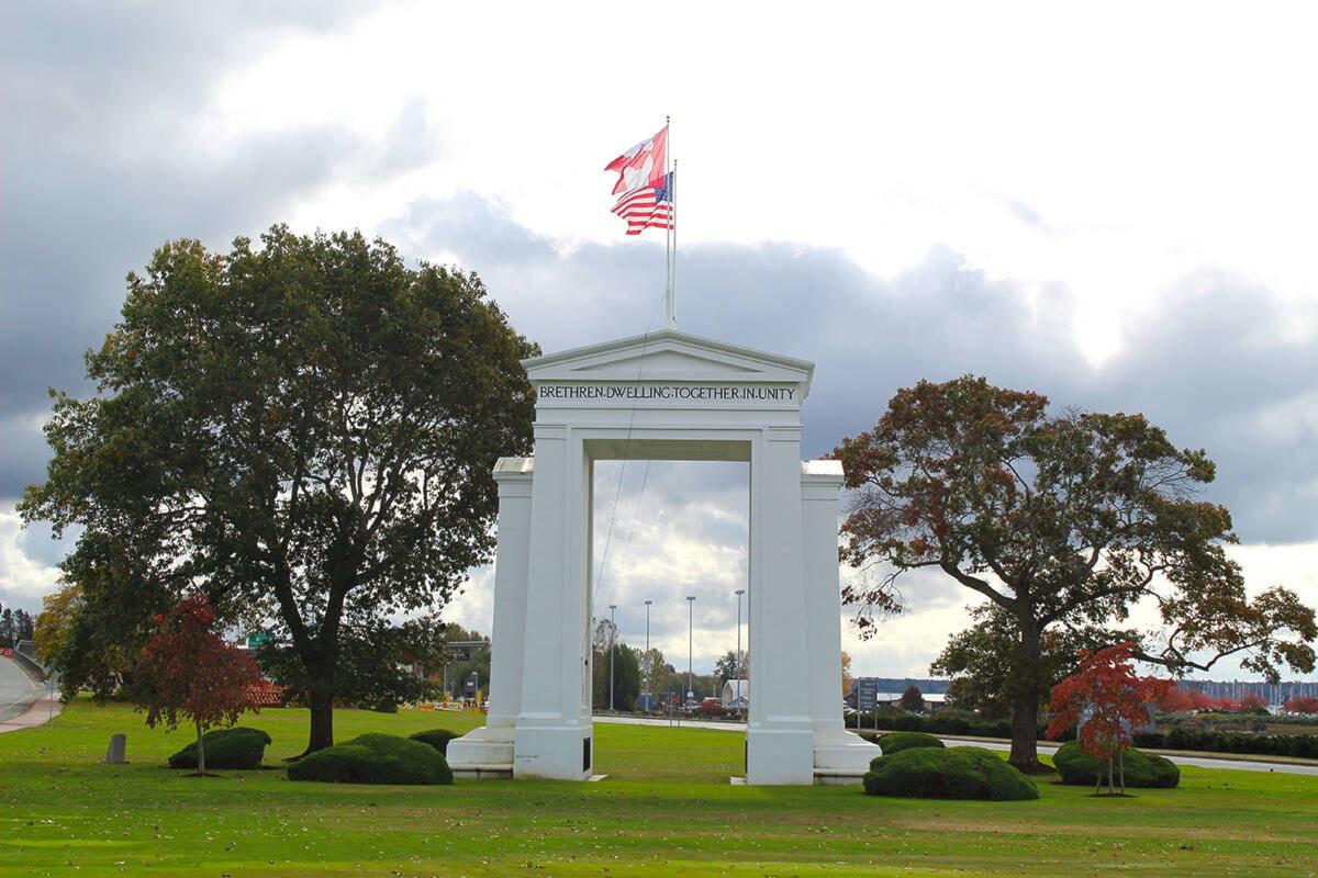 Peace Arch monument with Canadian and U.S. flags above, framed by trees at Peace Arch Park on the Canada–U.S. border.