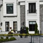 Police officers examine a South Surrey home damaged by gunfire during an extortion-related shooting, with yellow police tape surrounding the property — Surrey Speak coverage of B.C.’s extortion crisis.