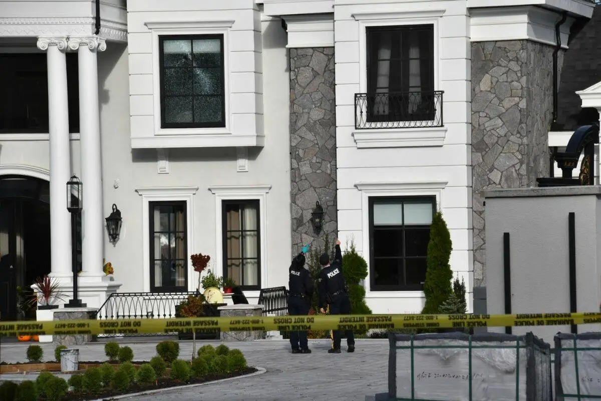 Police officers examine a South Surrey home damaged by gunfire during an extortion-related shooting, with yellow police tape surrounding the property — Surrey Speak coverage of B.C.’s extortion crisis.