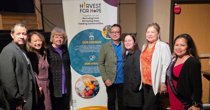 Community members standing together beside a Harvest for Hope banner at the Surrey fundraiser supporting food rescue and local families.