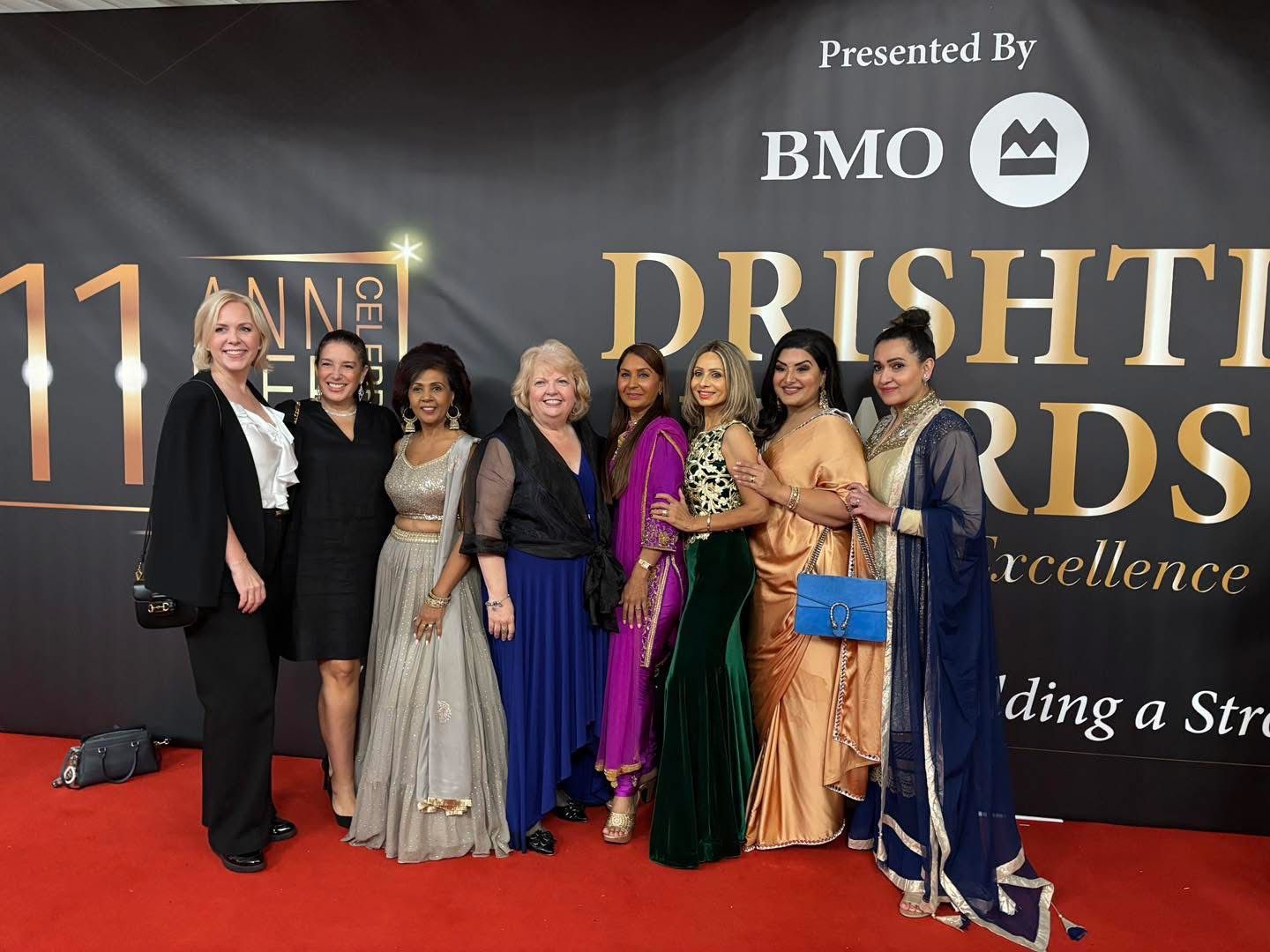 Group of guests posing on the red carpet at the 11th Drishti Awards Gala in Surrey, standing in front of the event backdrop presented by BMO.