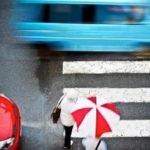Surrey Speak – Pedestrians crossing a wet crosswalk with vehicles passing by, illustrating Surrey’s new speed limit reductions and Vision Zero pedestrian safety measures.