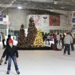 Families and children skating inside the Winter Ice Palace at Cloverdale Arena, surrounded by Christmas trees and festive lights.