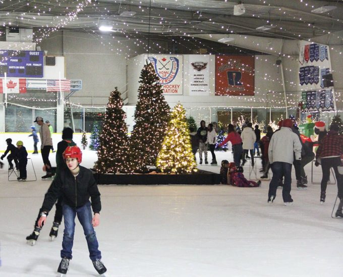 Families and children skating inside the Winter Ice Palace at Cloverdale Arena, surrounded by Christmas trees and festive lights.