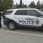 Surrey Police officers standing beside a Surrey Police Service SUV amid rising extortion cases in Surrey, as reported by Surrey Speak.