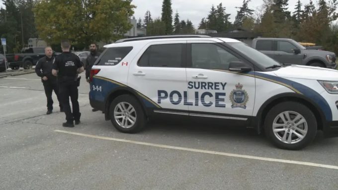 Surrey Police officers standing beside a Surrey Police Service SUV amid rising extortion cases in Surrey, as reported by Surrey Speak.