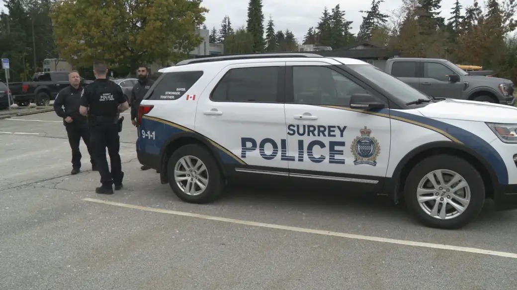 Surrey Police officers standing beside a Surrey Police Service SUV amid rising extortion cases in Surrey, as reported by Surrey Speak.