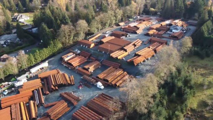 Aerial view of a Surrey industrial yard storing large steel pipes and materials, the site at the centre of a city injunction application over alleged bylaw violations.