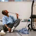 Performance artist Dana Michel interacts with office objects during a live presentation of MIKE at the Surrey Art Gallery.