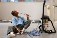 Performance artist Dana Michel interacts with office objects during a live presentation of MIKE at the Surrey Art Gallery.