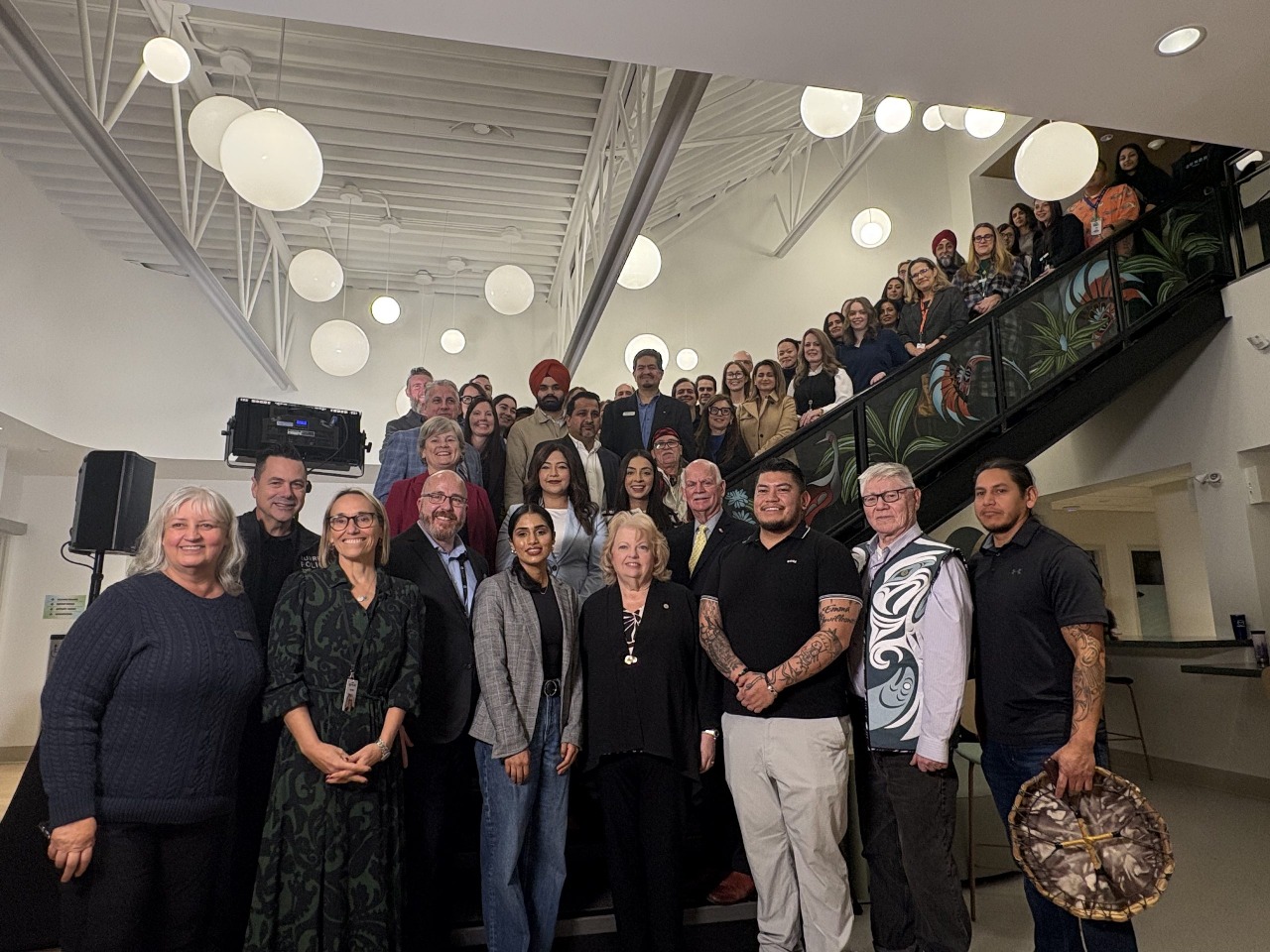 Large group photo at the Foundry Surrey Central opening event, with a civic leader standing at the center among community members, staff, and supporters.