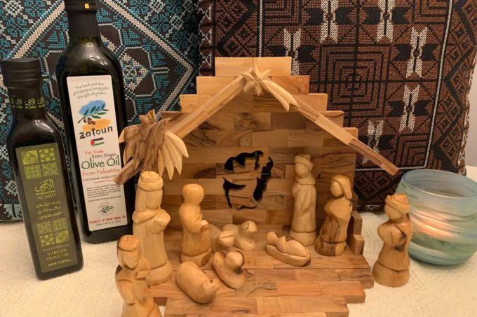 Handmade Palestinian olive-wood nativity set and olive oil bottles displayed at a South Surrey craft fair supporting West Bank artisans.