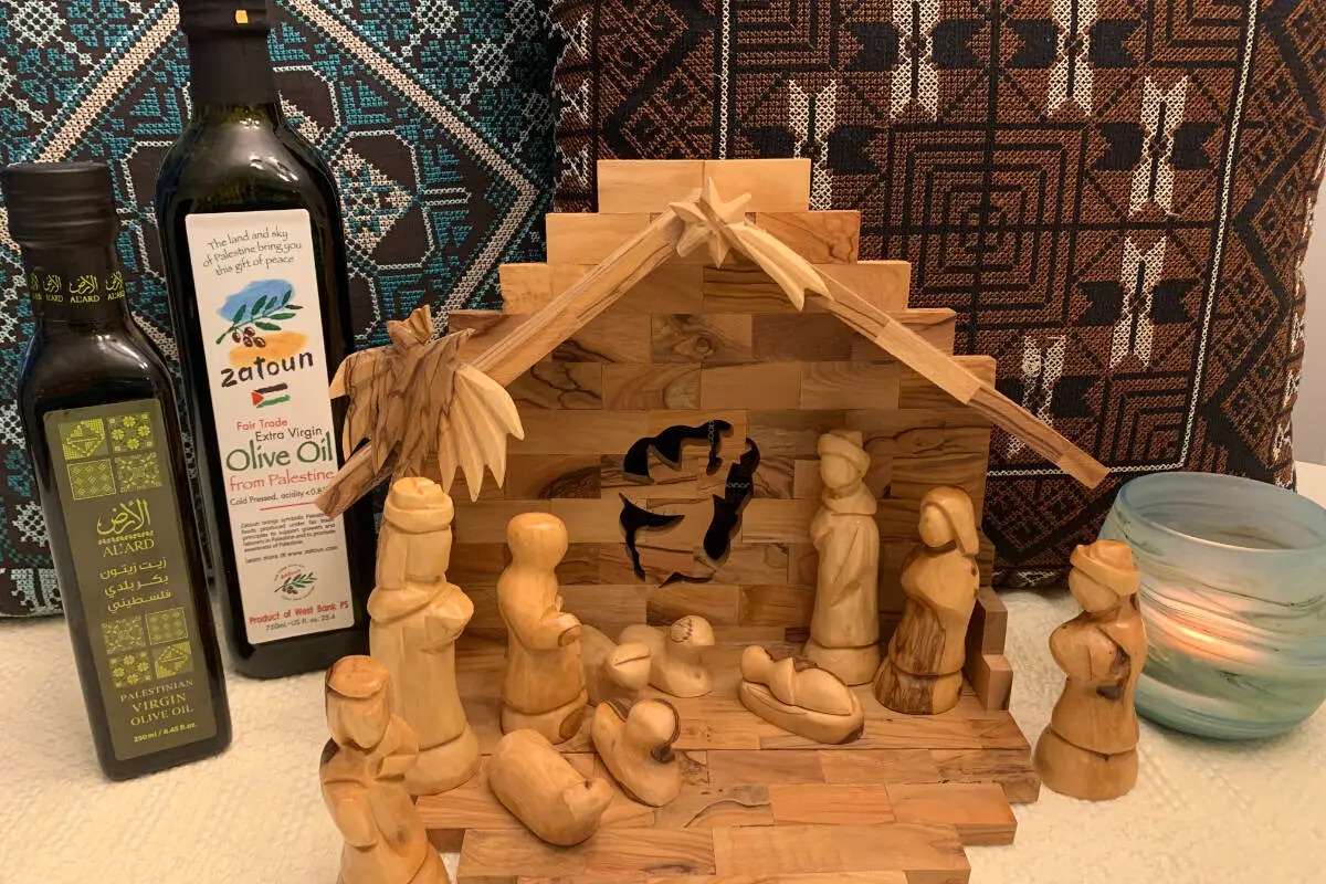 Handmade Palestinian olive-wood nativity set and olive oil bottles displayed at a South Surrey craft fair supporting West Bank artisans.