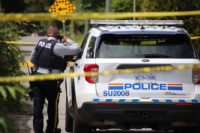 RCMP officer and police vehicle at a taped-off crime scene in Surrey during a homicide investigation.