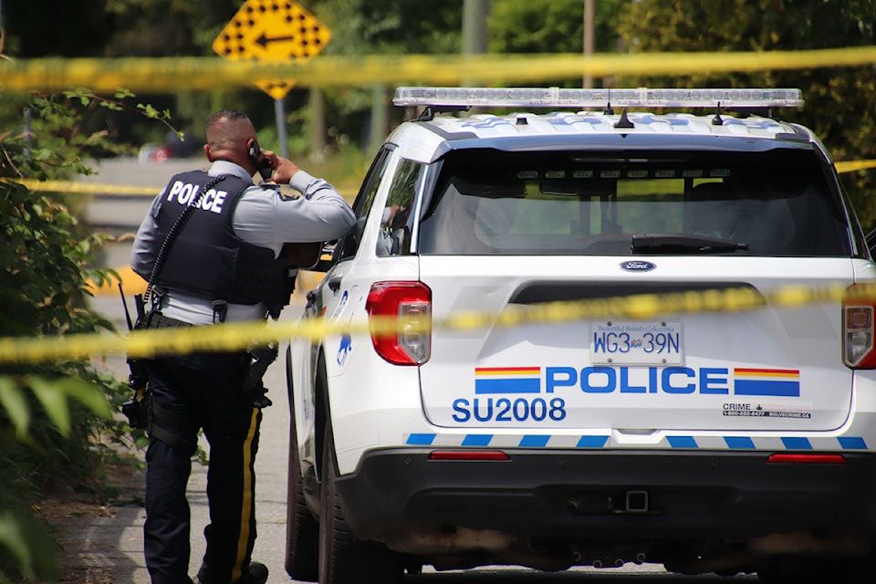 RCMP officer and police vehicle at a taped-off crime scene in Surrey during a homicide investigation.