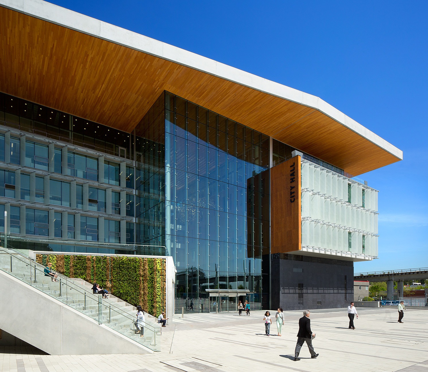 Exterior view of Surrey City Hall, showing the modern wood and glass facade with “City Hall” lettering.