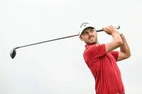 South Surrey golfer Adam Svensson follows through on a powerful tee shot while wearing a red shirt and white cap.