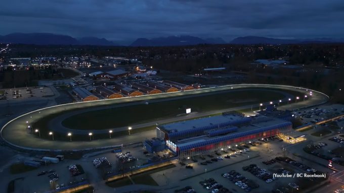 Night aerial view of Fraser Downs racetrack in Cloverdale, with the oval track and barns lit up under a dark sky.