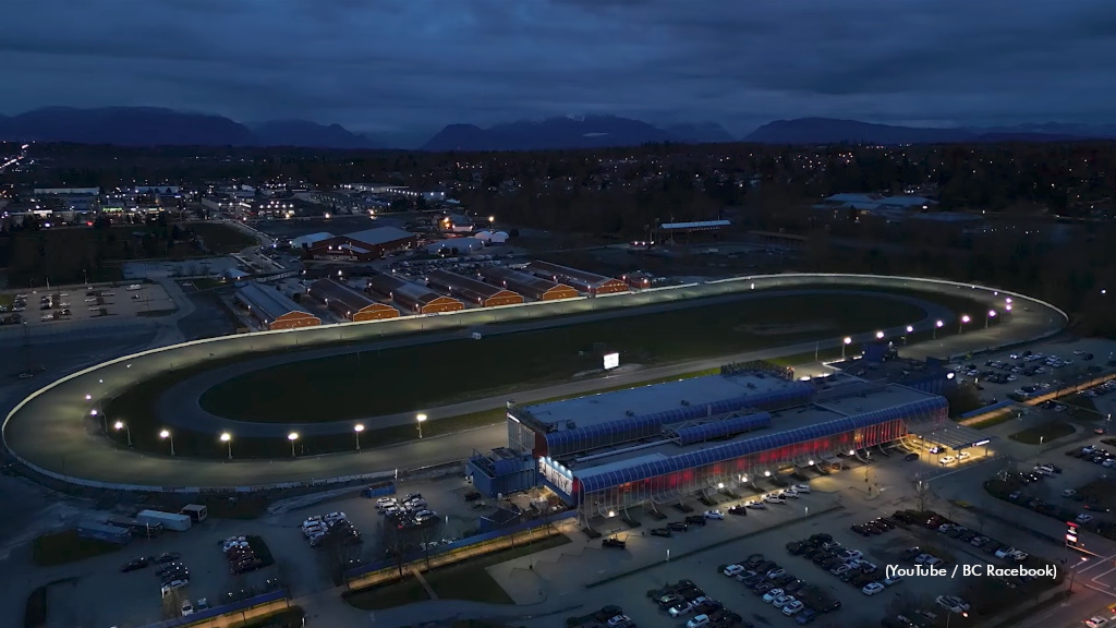 Night aerial view of Fraser Downs racetrack in Cloverdale, with the oval track and barns lit up under a dark sky.