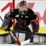 Calgary Hitmen goalie Eric Tu drops into the butterfly position in front of the net, tracking the puck during WHL action.