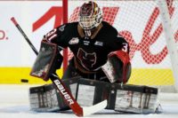 Calgary Hitmen goalie Eric Tu drops into the butterfly position in front of the net, tracking the puck during WHL action.