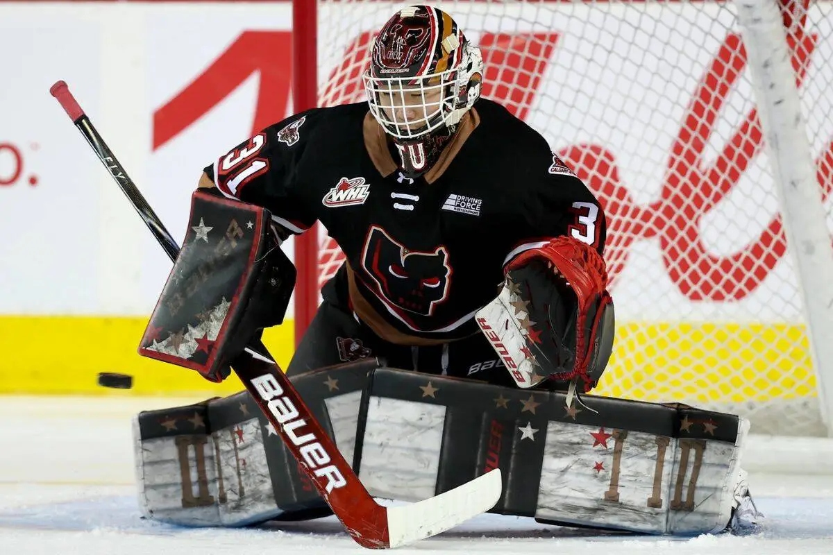 Calgary Hitmen goalie Eric Tu drops into the butterfly position in front of the net, tracking the puck during WHL action.