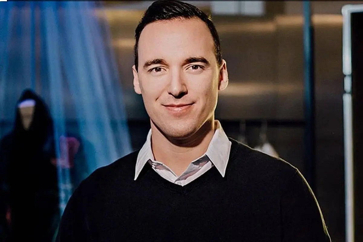 Portrait of teacher Lev Mihalik standing indoors in a dark sweater and collared shirt, winner of UBC’s 2025 Alumni Educator of the Year Award.