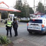 Surrey Police Service officers and a patrol SUV outside a taped-off Chevron gas station in Surrey.