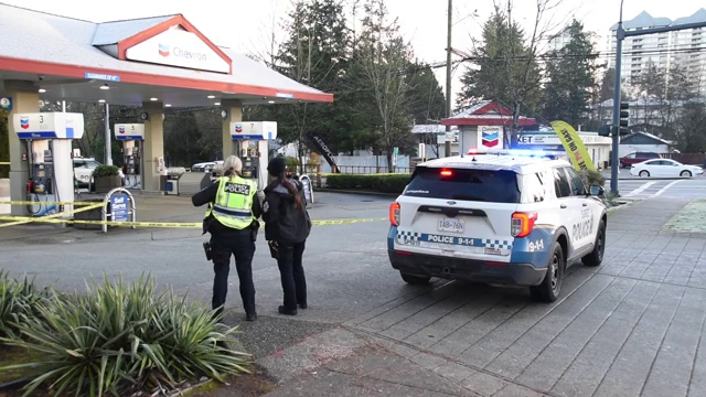 Surrey Police Service officers and a patrol SUV outside a taped-off Chevron gas station in Surrey.