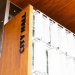Exterior view of Surrey City Hall, showing the modern wood and glass facade with “City Hall” lettering.