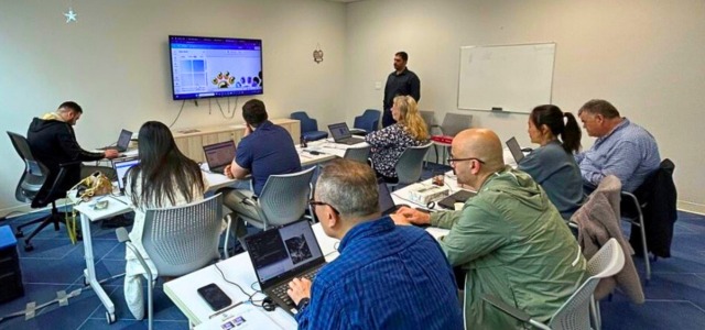 Business owners attending a hands-on AI training workshop at Surrey Libraries’ City Centre Branch, with a facilitator guiding them using laptops and a presentation screen.