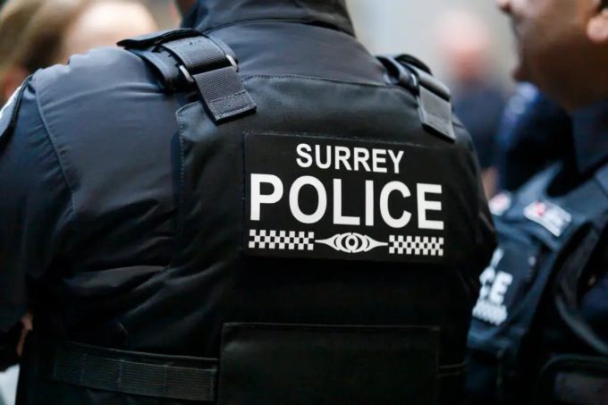 Back view of a Surrey Police Service officer wearing a tactical vest with “Surrey Police” written across it.