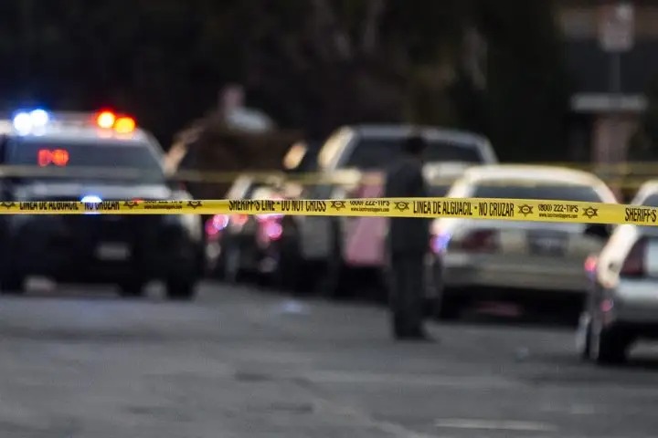Police vehicles and yellow crime scene tape block a residential street, illustrating a serious incident under investigation in Surrey.