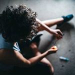 Person sitting on the floor showing signs of drug overdose amid British Columbia’s growing overdose crisis