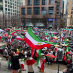 Large crowds gather in downtown Vancouver holding Iranian flags during a protest near the Vancouver Art Gallery.
