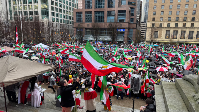 Large crowds gather in downtown Vancouver holding Iranian flags during a protest near the Vancouver Art Gallery.