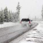 White Car on road in snowstorm surrounded by snow
