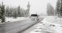 White Car on road in snowstorm surrounded by snow