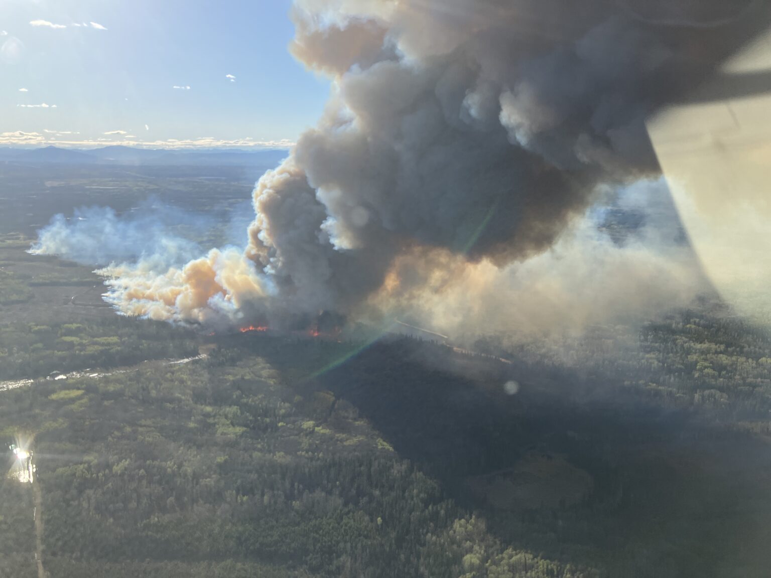 Smoke rising from active wildfires in British Columbia following lightning strikes during storm activity.