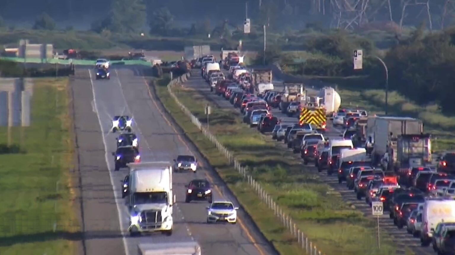 Emergency vehicles responding to a crash scene on Highway 99 in Surrey with heavy traffic nearby.