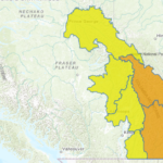 Dark storm clouds and heavy rain over southeastern British Columbia indicating flood watch conditions.