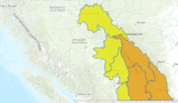 Dark storm clouds and heavy rain over southeastern British Columbia indicating flood watch conditions.