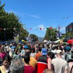 Large crowd attending Vancouver’s Italian Day festival with cultural decorations, food vendors, and entertainment.