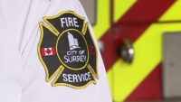 Firefighters responding to house fire in Surrey with smoke and emergency vehicles visible